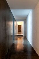 Um corredor estreito e pouco iluminado com uma porta de madeira no final.