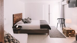Una camera da letto moderna con un letto, un comodino, una lampada e una TV a parete.