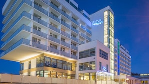 Een hotel met meerdere verdiepingen, balkons, een opvallend 'Baltyk'-bord en een modern architectuurontwerp.