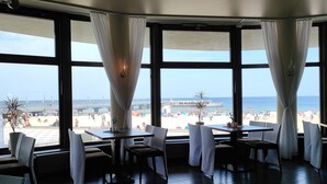 Een restaurant met grote ramen met uitzicht op een strand.