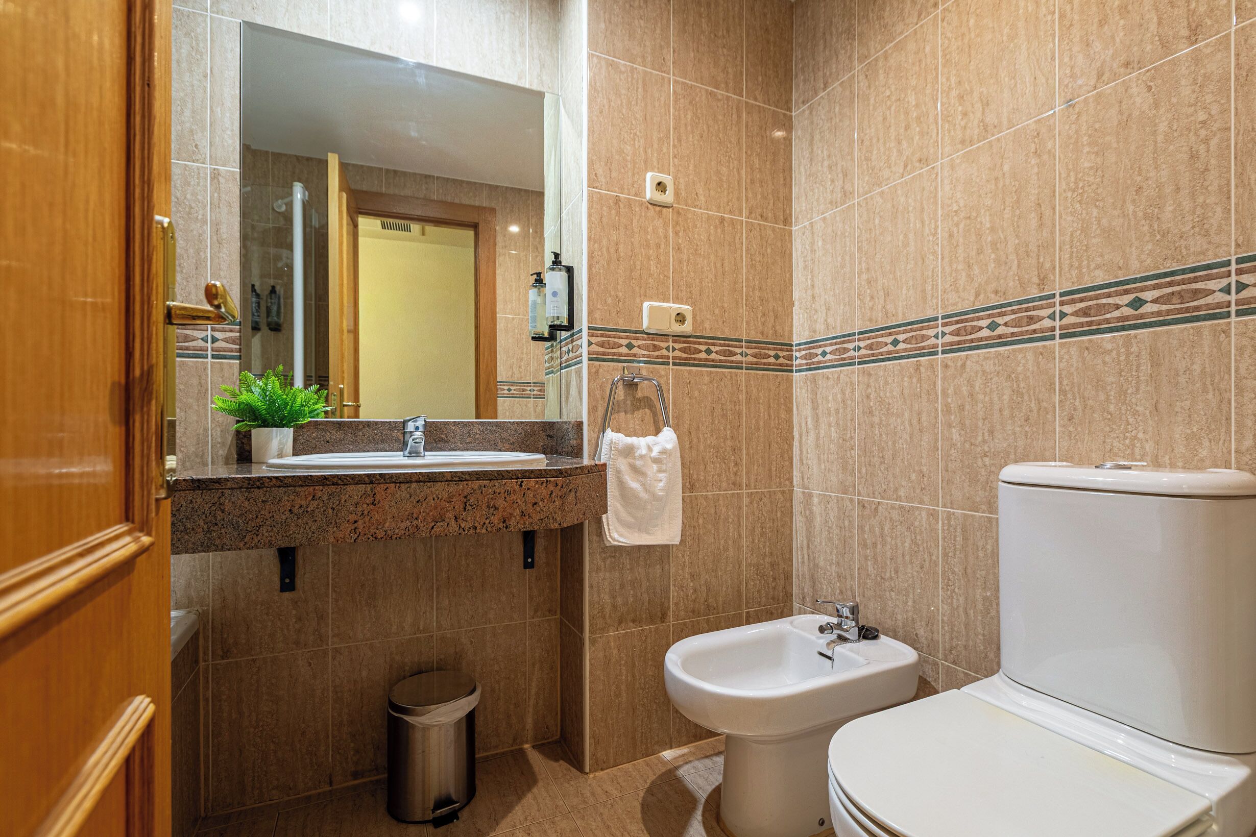 Un baño con lavamanos, bidé, inodoro y cubo de basura.