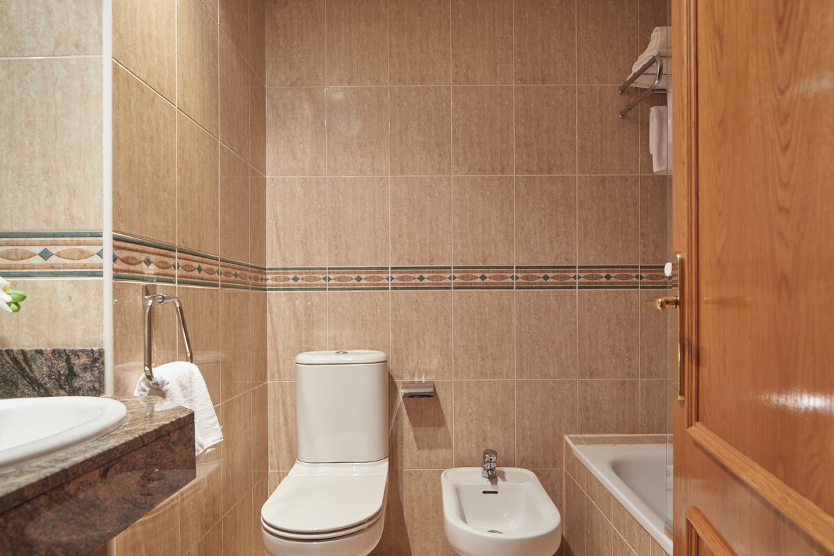 A bathroom with a toilet, bidet, sink, and bathtub.