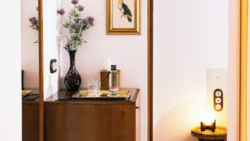 Um balcão de madeira com um vaso de flores, um quadro emoldurado e uma pequena mesa com uma luz.