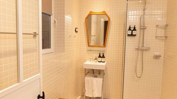Un baño pequeño con ducha, lavamanos y espejo.