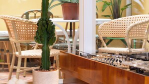 A cactus in a pot on a wooden counter, wicker chairs, and a table with a potted plant. - Hotel du Temps Madrid (Madrid)