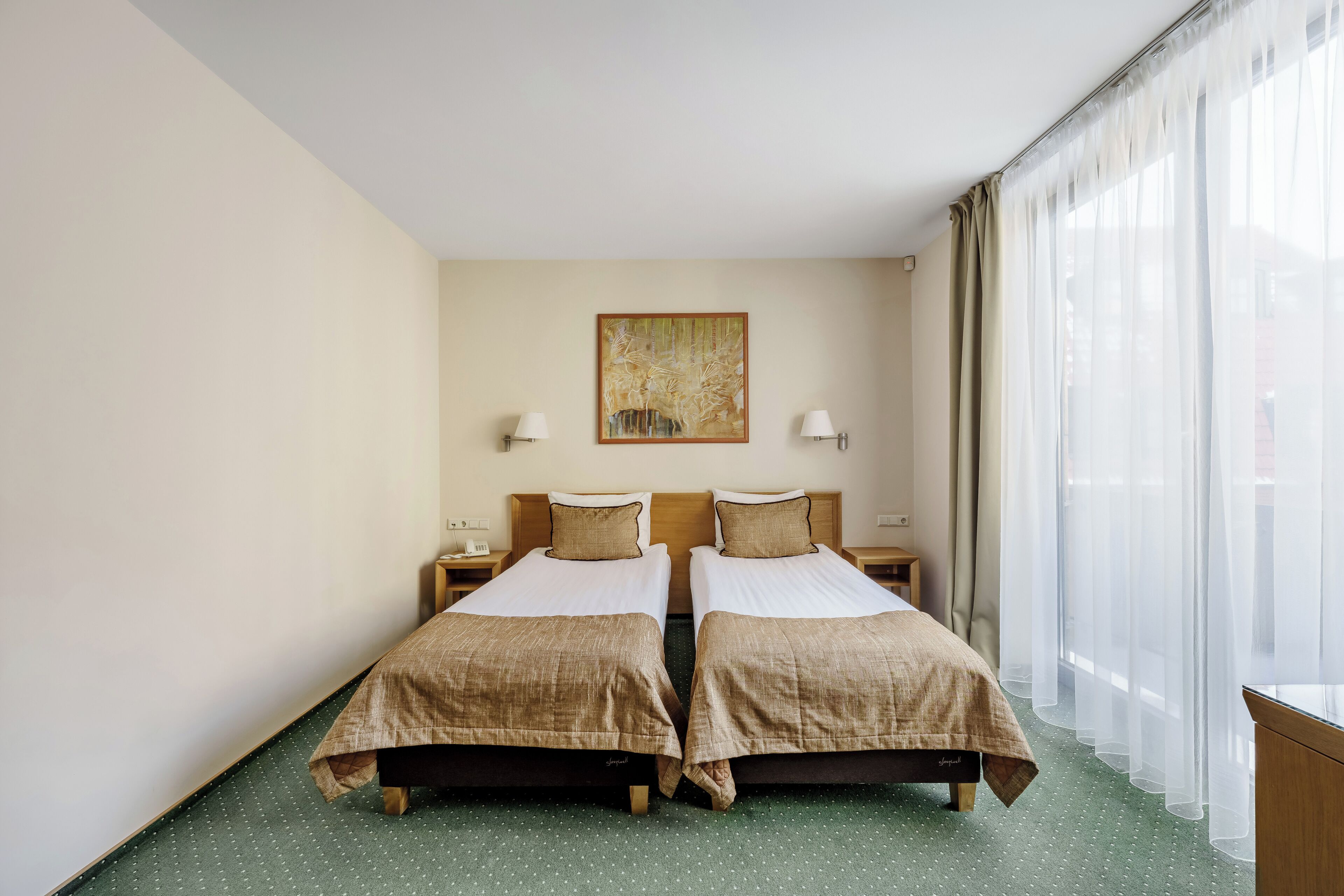 Una habitación de hotel con dos camas, un cuadro en la pared y una ventana con cortinas.