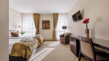 Habitación de hotel con dos camas, un escritorio, una silla, un televisor y un cuadro en la pared.