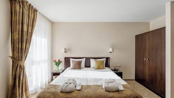 A hotel room with a large bed, two bedside tables, a wardrobe, and a curtain.