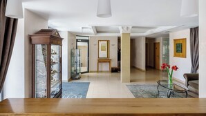 Uma sala de estar ampla com uma mesa de centro de madeira, um aparador de vidro e uma mesa de centro de vidro com flores vermelhas.