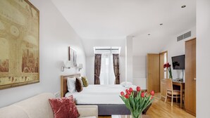 Quarto de hotel com cama, sofá, escrivaninha e televisão.