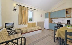 Cozy living space with a sofa, TV, and kitchenette featuring a refrigerator, stove, and coffee maker.