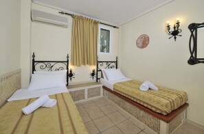 Two single beds with wall-mounted nightstands and lamps, set against a traditional backdrop.