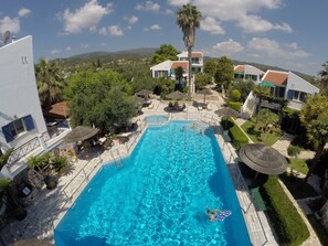 Relax by the resort's clear blue pool surrounded by lush gardens and outdoor seating areas.