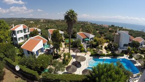 A resort with multiple villas, a swimming pool, and a view of the sea. - Paris Village (Messini)