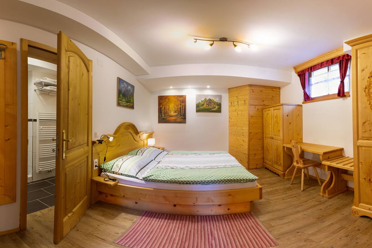 Un dormitorio acogedor con cama de madera, un escritorio y un armario.