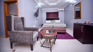 Une chambre à coucher comprenant un lit, un bureau avec un ordinateur portable, une chaise, une armoire et un téléviseur.