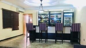 Un coin bar avec des chaises à rayures, un comptoir avec des bouteilles et un ventilateur au plafond.