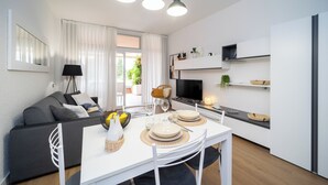 Una sala moderna con sofá, mesa de comedor y zona de cocina.