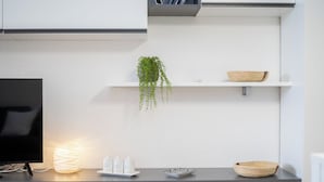 Una cocina moderna con un televisor de pantalla plana, una lámpara empotrada, una planta en maceta y cuencos decorativos en la encimera.