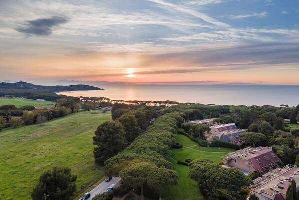 An aerial view of a residential area with houses, green spaces, and a body of water. - Scoglietto 50 (Castiglione della Pescaia)