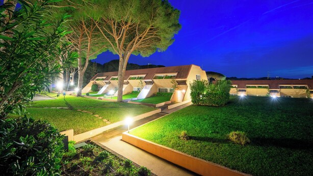 Un espacio exterior bien iluminado con un camino que lleva a un edificio con varias puertas de garaje.