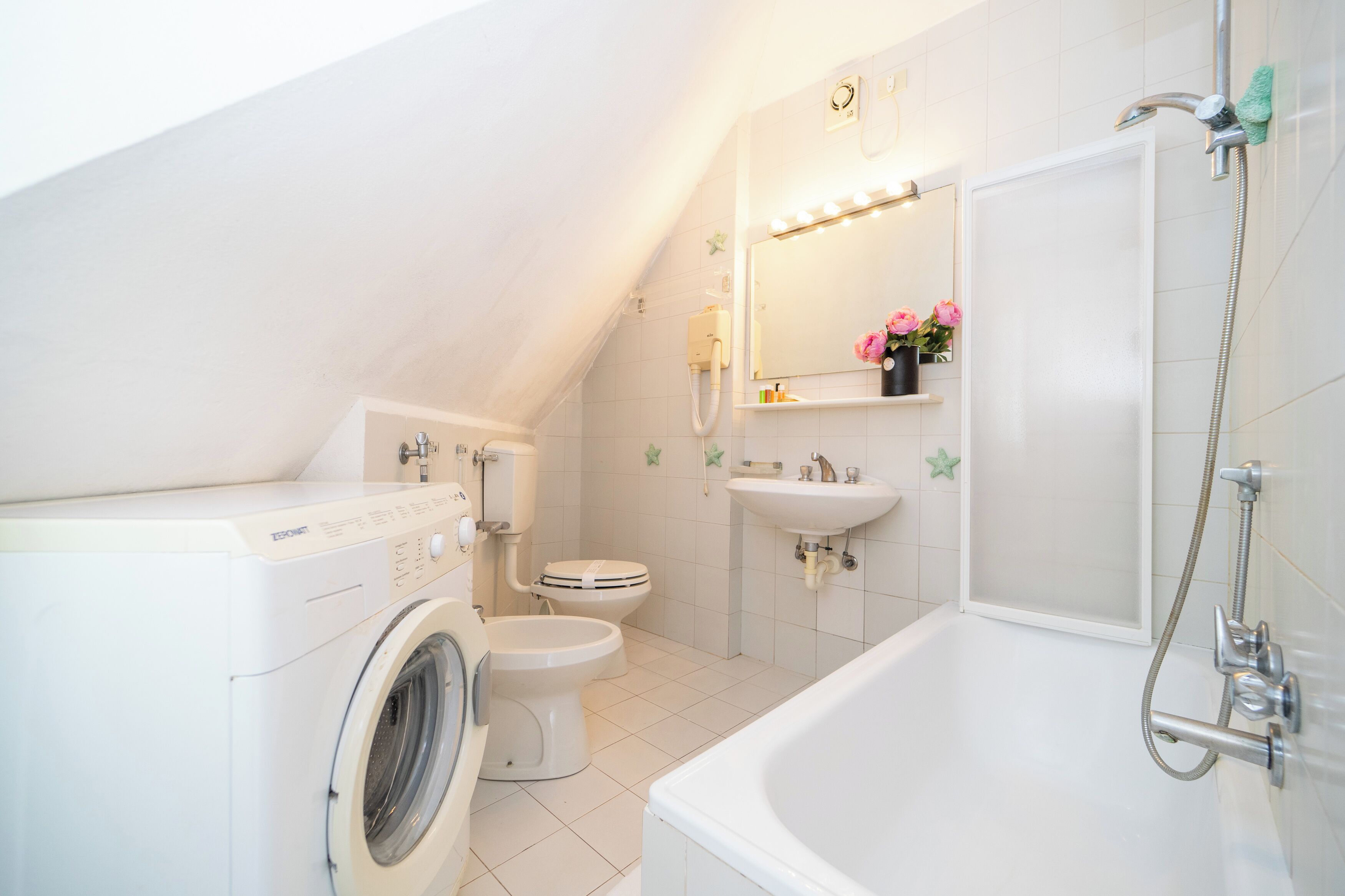 Een moderne badkamer met een wasmachine, toilet, wastafel en bad.