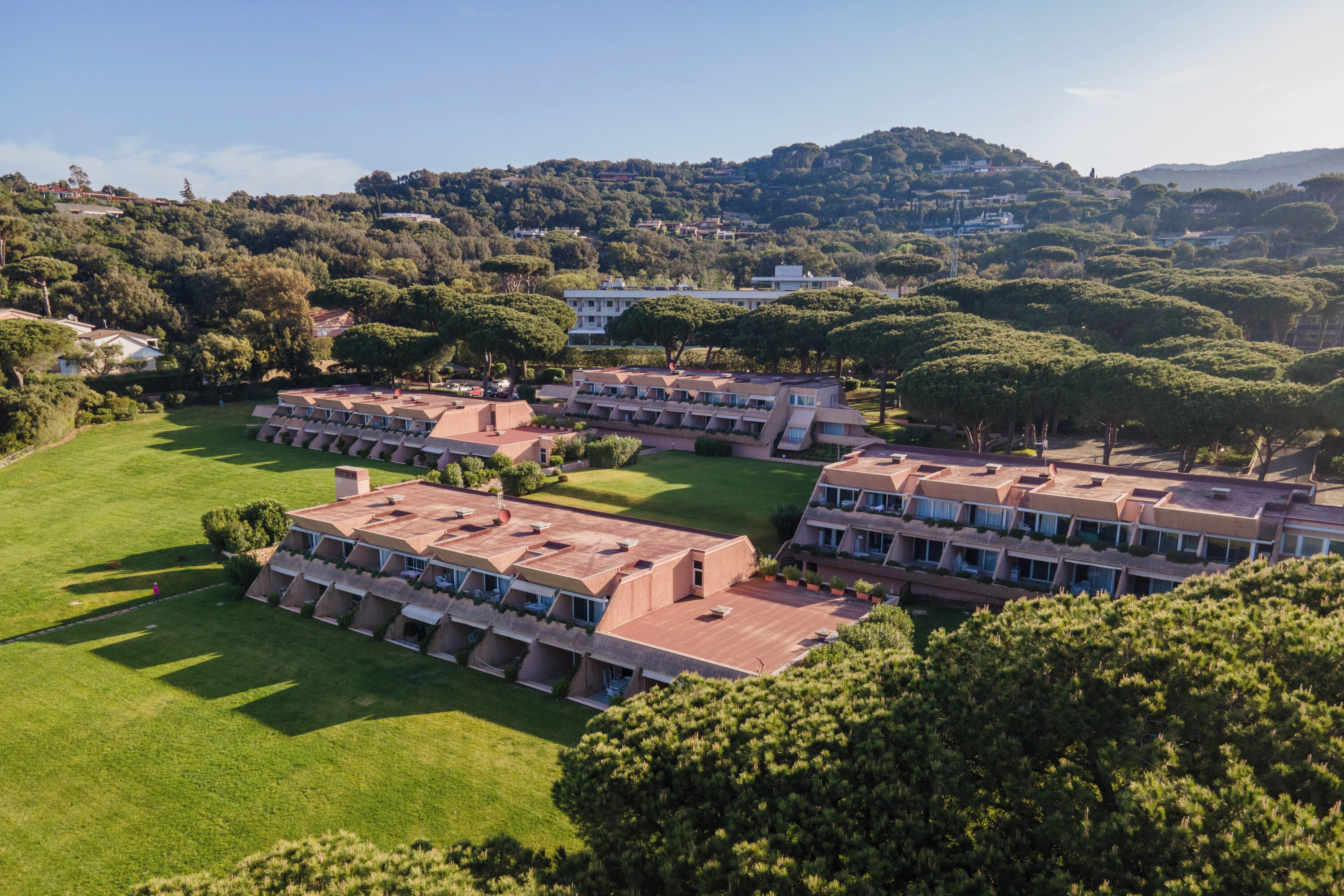 Un hotel con varias construcciones, dispuestas en línea, con un césped verde al frente.