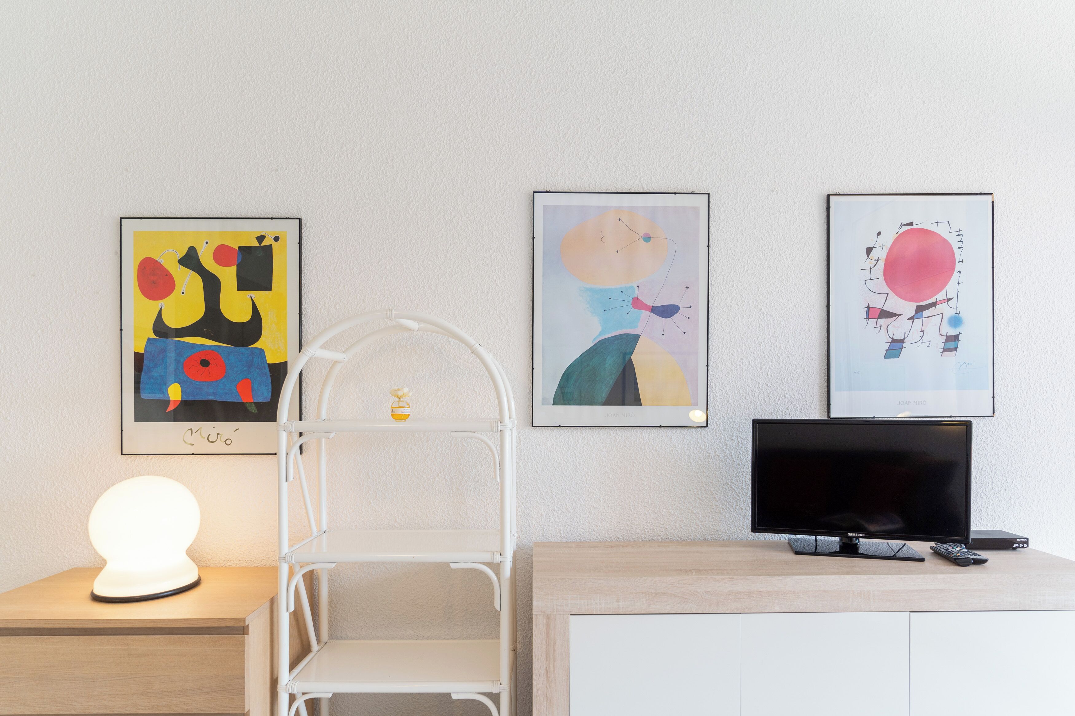 Une chambre avec un lit, une table de chevet, une lampe et un téléviseur posé sur un meuble.