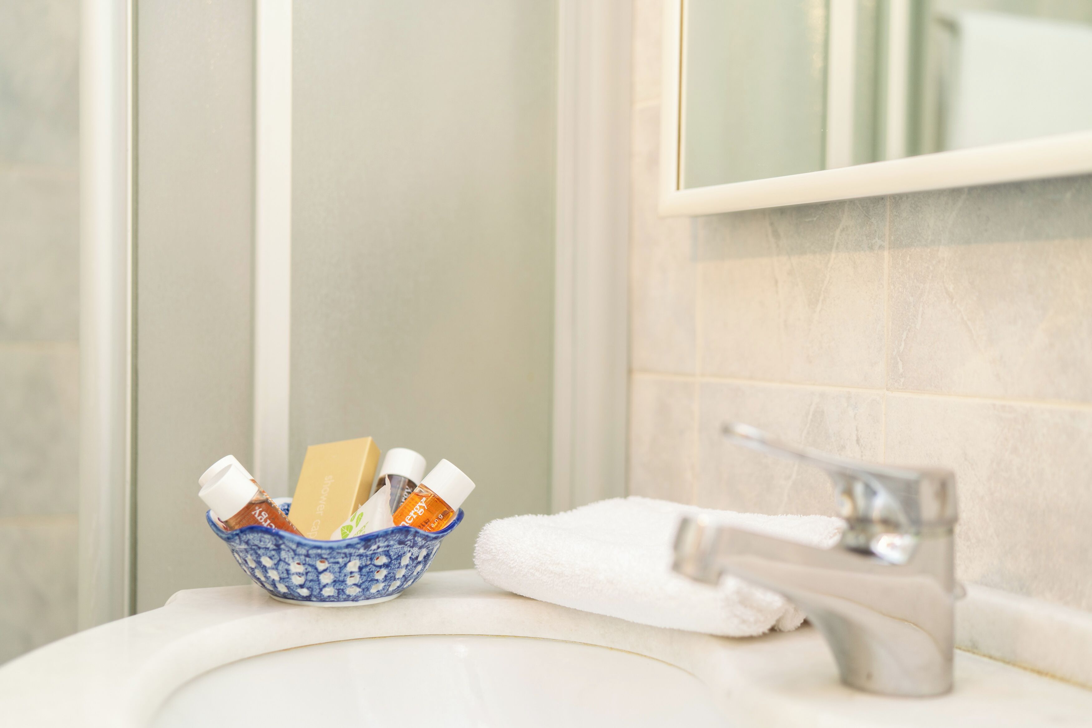 Un lavabo de salle de bain avec une serviette blanche et un bol en céramique bleue contenant des articles de toilette.