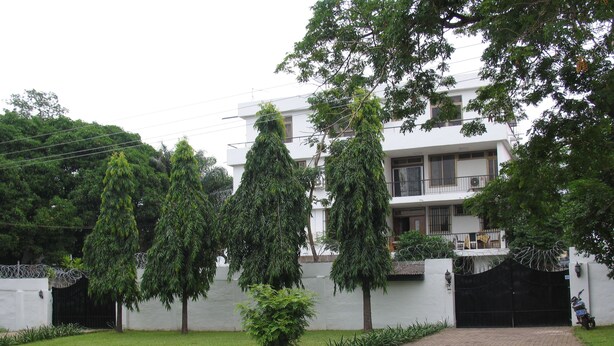 A modern two-story building with a white exterior, a gated entrance, and a paved driveway. - Kwesi Affum Apartments (Accra)