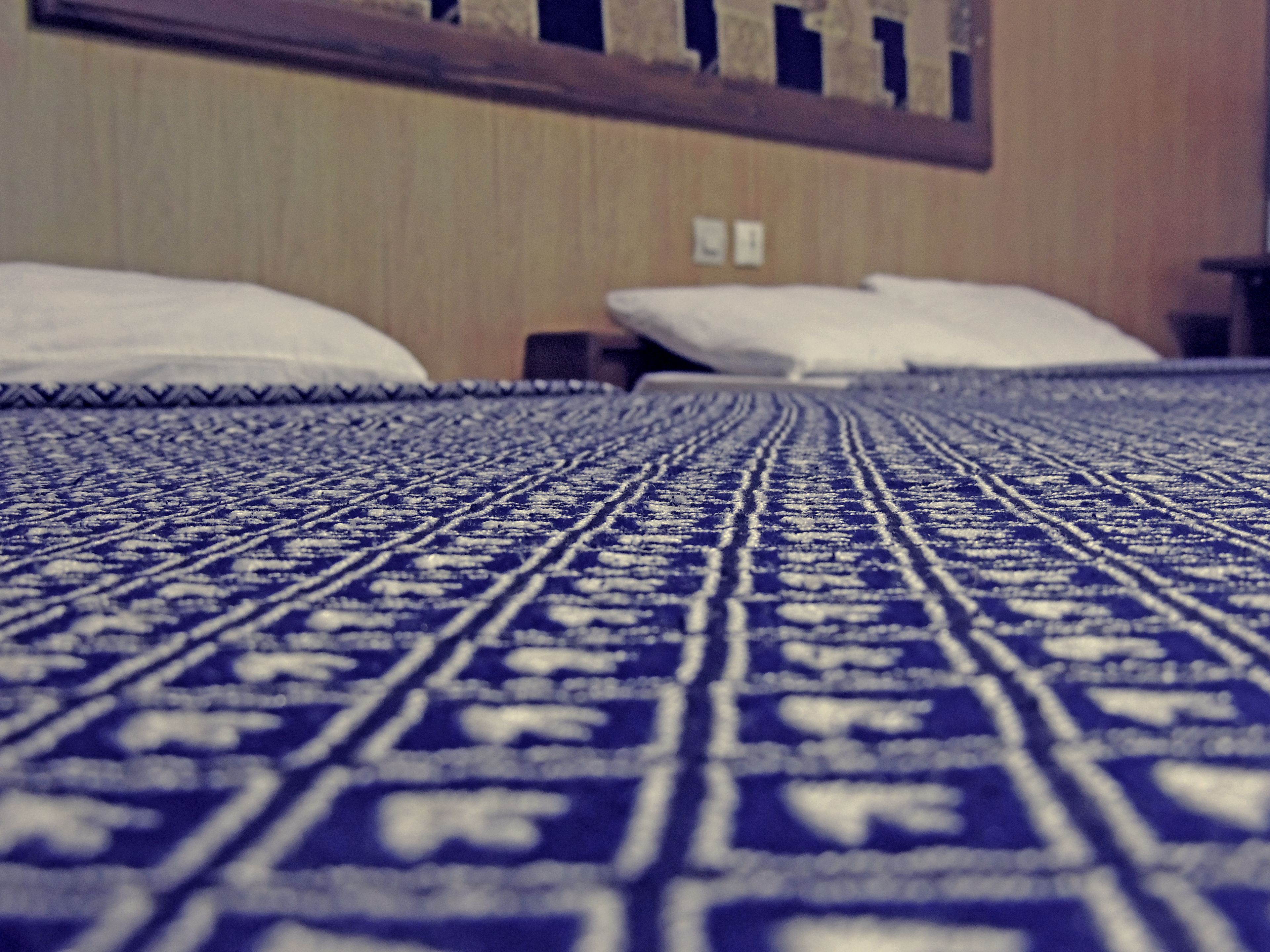A bed with a patterned bedspread and pillows.