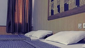 A hotel room with two beds, a patterned bedspread, a window with curtains, and a wall with a decorative panel. - Saffana Hôtel (Douala)