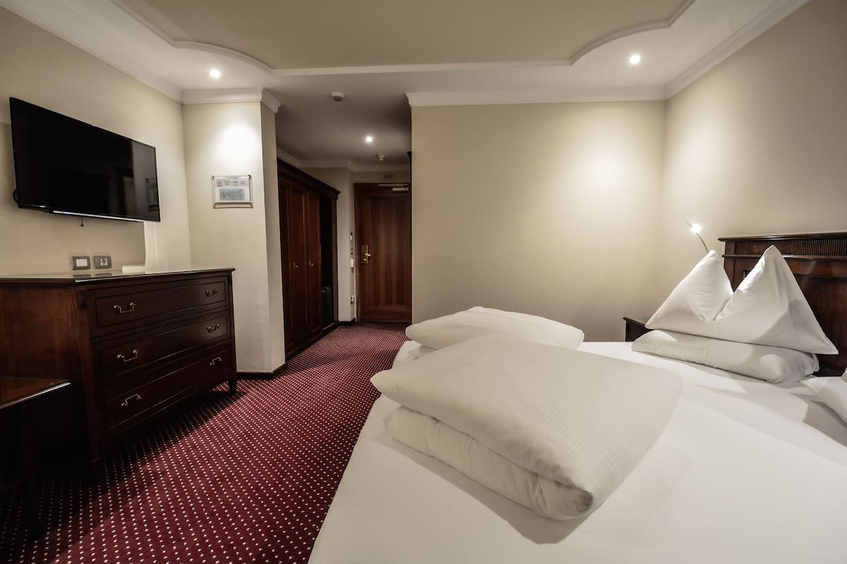 Habitación de hotel con una cama, cómoda, televisor de pantalla plana y un pasillo que conduce a otra habitación.