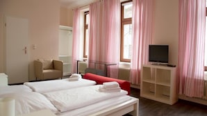 Une chambre d’hôtel avec deux lits, une télévision, un canapé et un fauteuil.