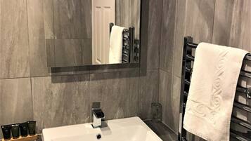 Un baño con un lavabo blanco, un espejo y un perchero para toallas.