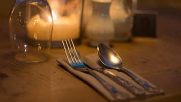 A table set with a fork, spoon, and knife, a glass pitcher, and a candle.
