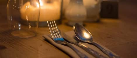 A table set with a fork, spoon, and knife, a glass pitcher, and a candle.