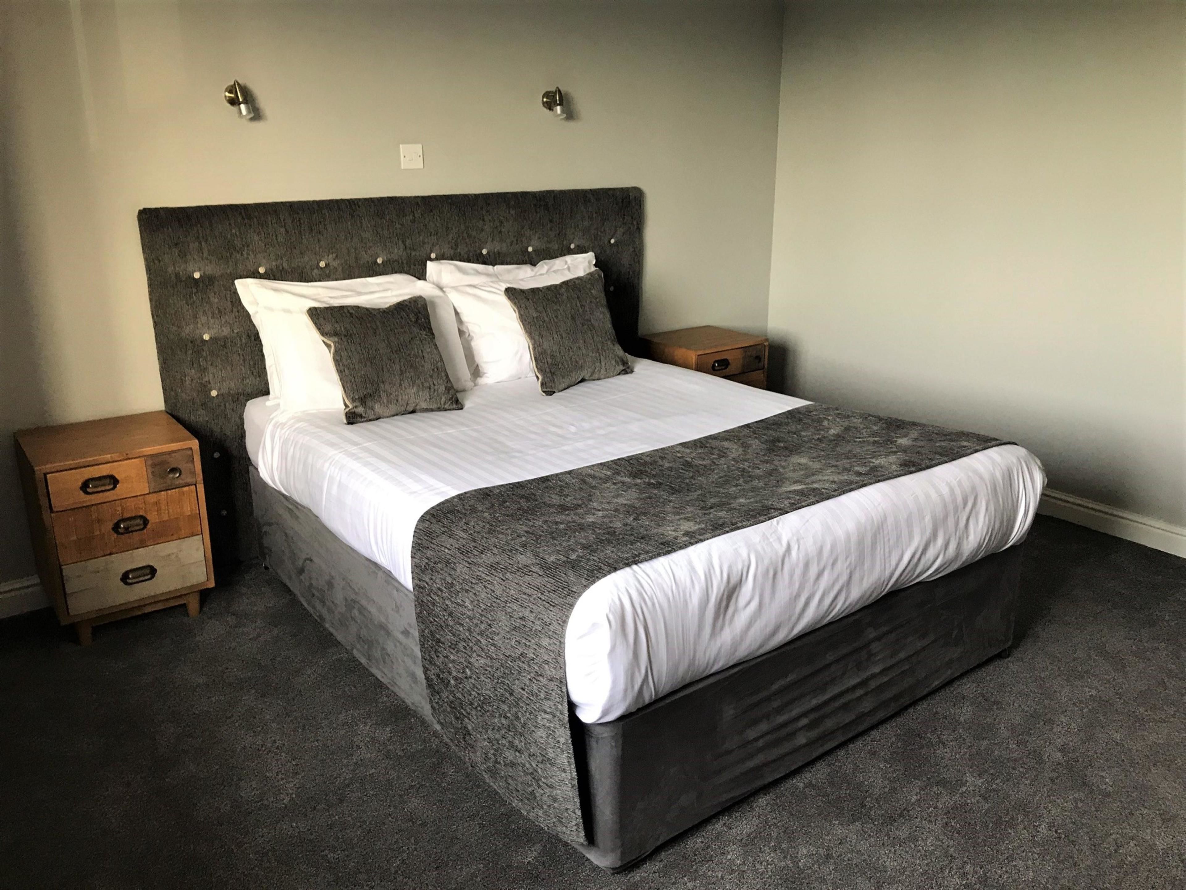 Ein Schlafzimmer mit einem großen Bett, zwei Nachttischen und einem dunklen Kopfteil.