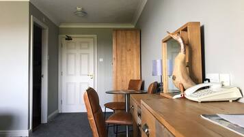 Une pièce comprenant une commode en bois, un téléphone, un miroir et une table à manger avec des chaises.