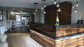 A reception desk with a wooden finish and a modern light fixture above it.