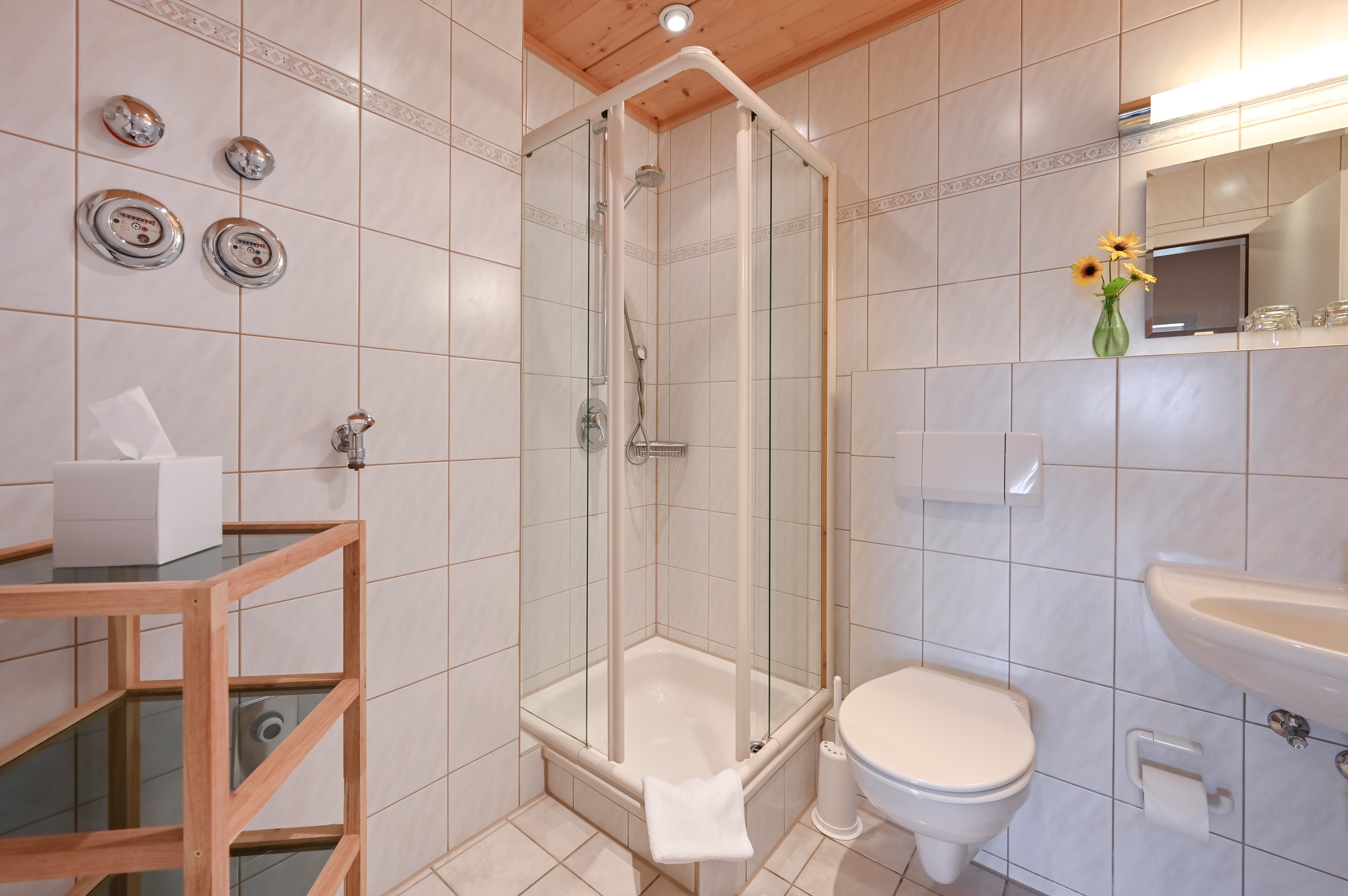 A bathroom with a glass-enclosed shower, a toilet, and a sink.