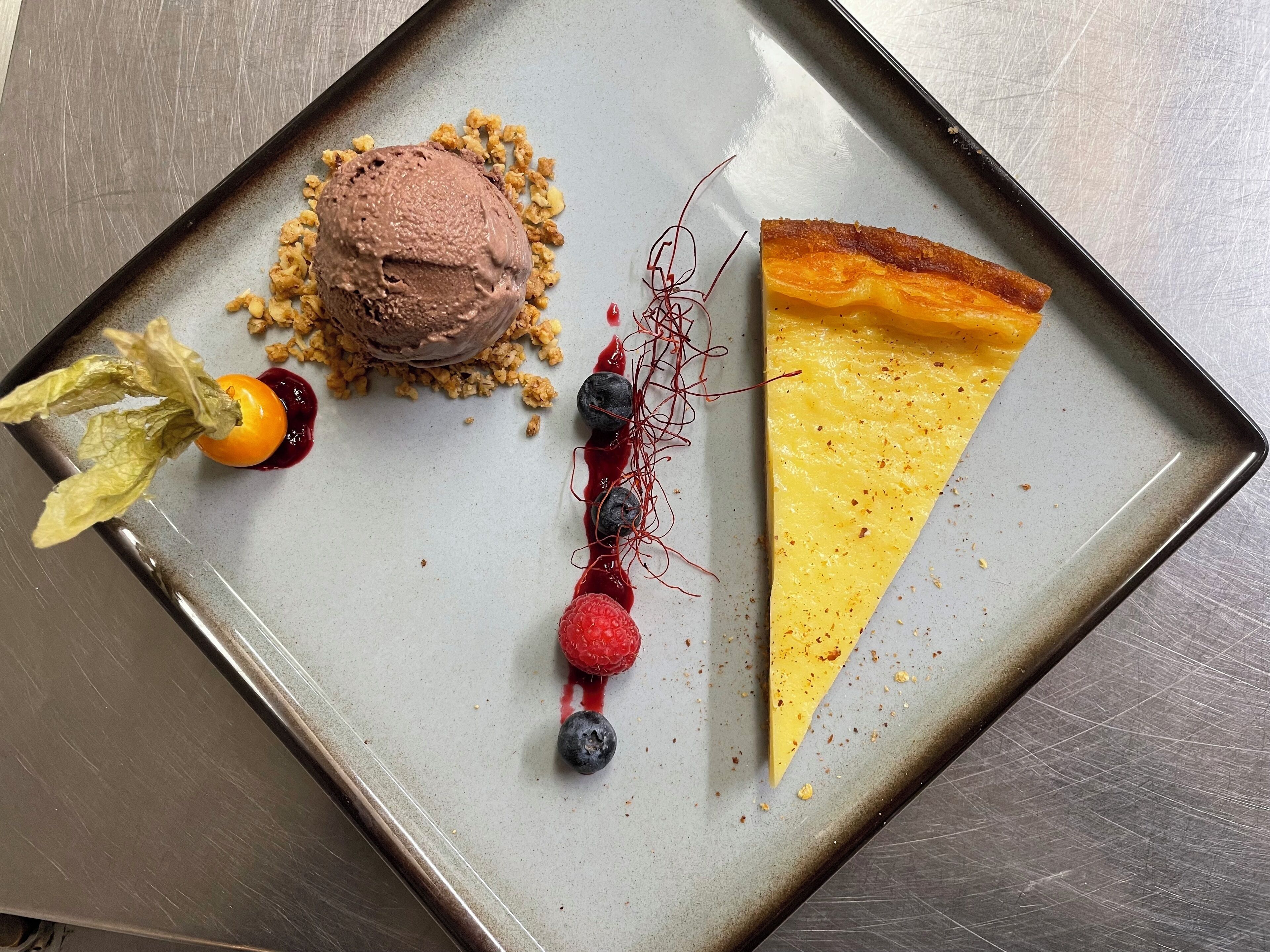 A dessert plate with a slice of pie, a scoop of ice cream, and a decorative arrangement of berries and leaves.