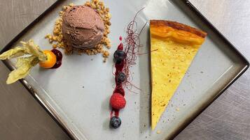 A dessert plate with a slice of pie, a scoop of ice cream, and a decorative arrangement of berries and leaves.