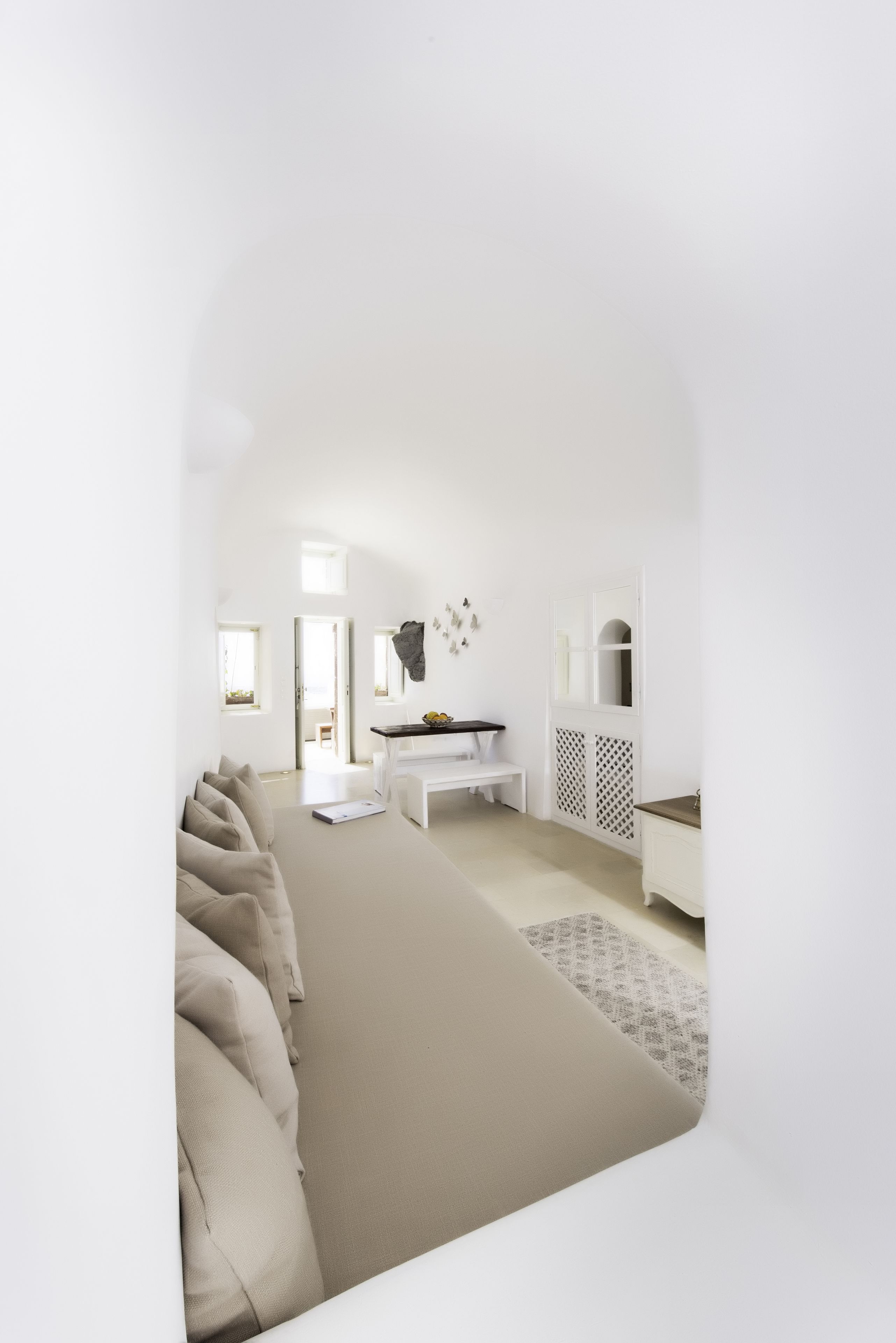 A modern, minimalist room with a large bed, a desk, and a wardrobe.