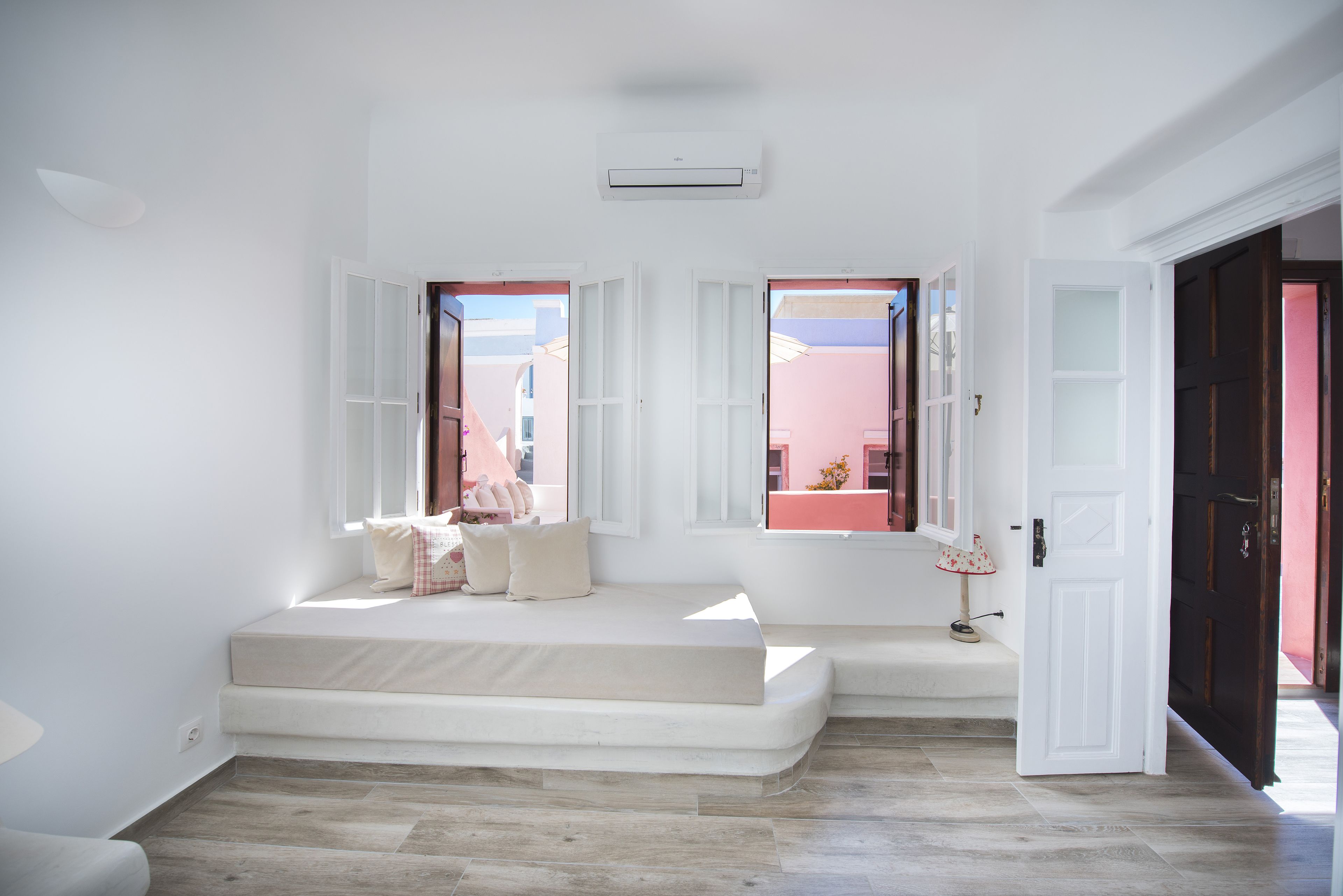 A bright room with a white bench, a lamp, and a door leading outside.