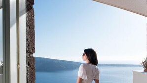 A woman in a white dress standing on a balcony overlooking a sea view. - Anemi House & Villas (Santorini)