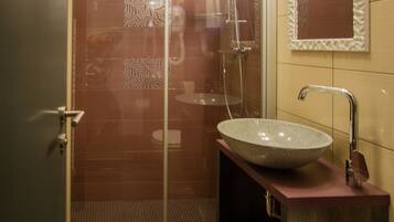 Un bany modern amb plat de dutxa de vidre, un lavabo sobretaulella i un vàter.