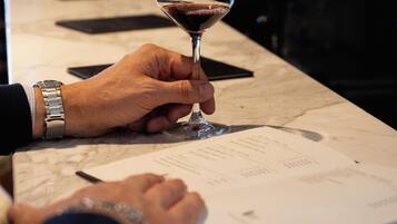A person holding a wine glass, with a menu and a bottle in the background.