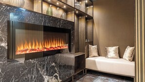 A modern living room with a fireplace, a sofa with cushions, and a wooden wall panel. - Hotel Royal Prague (Prague)