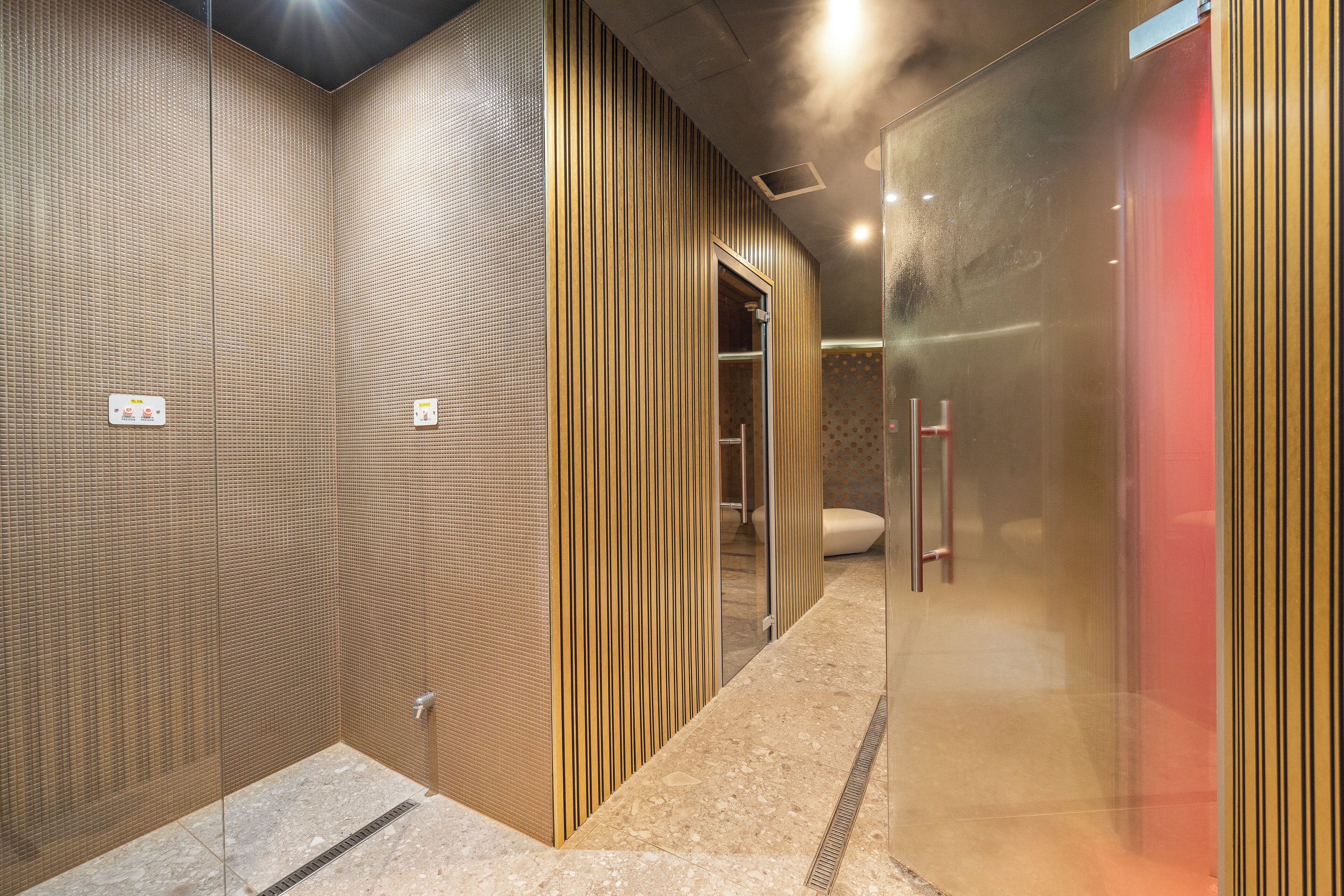A modern bathroom with a tiled wall, a glass shower enclosure, and a wooden panel design.